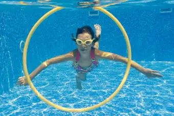 niña nadando bajo el agua en la piscina por aro