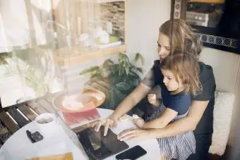 Madre usando laptop e hija sentada en el regazo