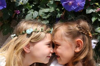 Dos hermosas hermanas ríen y juegan frente a hermosas flores de color púrpura