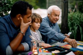 Familia multigeneracional jugando juegos de mesa mientras se sienta a la mesa en el patio trasero