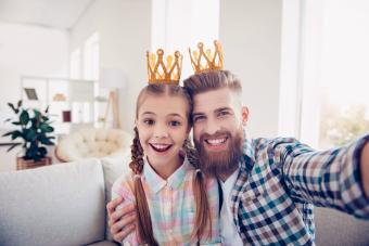 Niño lindo y papá elegante con coronas mientras toma selfie