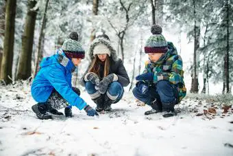 Niños viendo huellas de animales en la nieve en el bosque de invierno