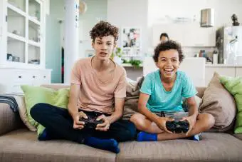 Dos hermanos sentados en un sofá jugando videojuegos