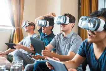 Grupo de amigos sentados en el sofá jugando con auriculares de realidad virtual