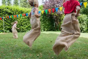 Niños haciendo una carrera de sacos en el jardín en una fiesta de cumpleaños