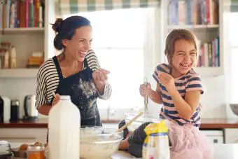 niña divirtiéndose horneando con su madre en la cocina