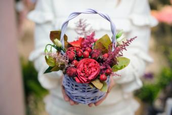 Bonita cesta de mimbre con composición floral en tonos rojos