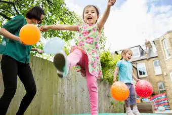 Madre e hijas jugando en el jardín con globos.