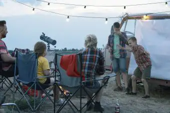 Personas con niños jugando a las charadas en el camping.