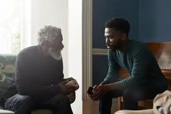 Padre e hijo hablando mientras están sentados en la sala de estar 