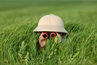 niño pequeño en hierba alta buscando algo