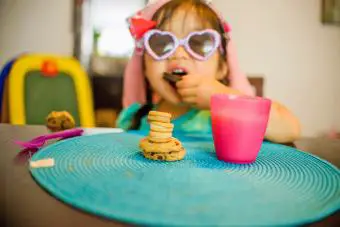 Chica sentada a la mesa con bebida y galletas