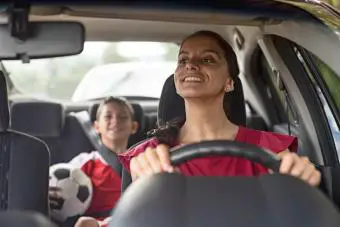 Mamá feliz del fútbol que lleva al bebé a la práctica de fútbol en su coche