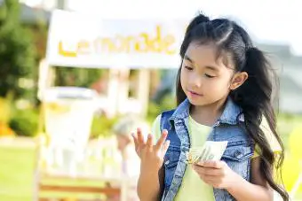 Una niña cuenta el dinero obtenido en un puesto de limonada