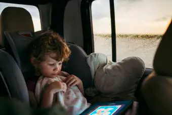 Niña jugando un juego en una tableta en el auto