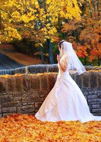 Una novia caminando por las hojas de otoño en el parque
