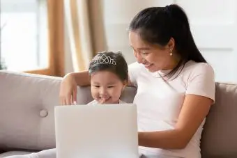 Madre joven y pequeña hija usando laptop juntos