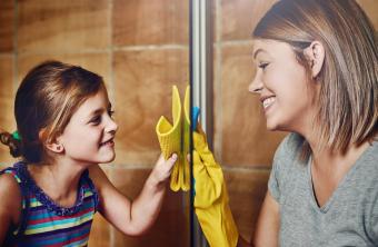 Mamá e hija limpian una ducha de vidrio