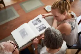 Mujer con sus padres mirando en un álbum de fotos.