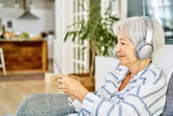 Anciana usando auriculares con teléfono inteligente