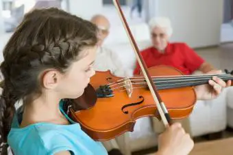 Niña tocando el violín para los abuelos.