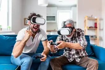 Padre e hijo en auriculares VR jugando videojuegos en el sofá en casa 