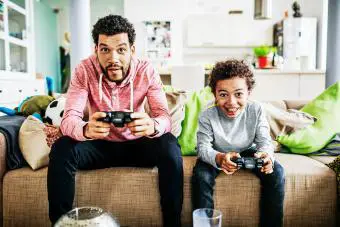 Padre e hijo enfocándose mientras juegan videojuegos juntos