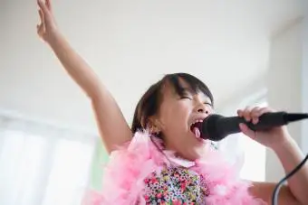 Chica cantando karaoke en la sala de estar