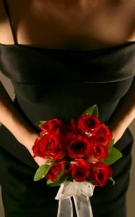 Dama de honor con un vestido negro que lleva rosas rojas
