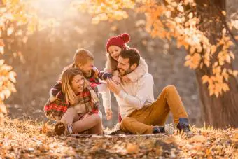 Una familia divertida divirtiéndose en el parque el día de otoño