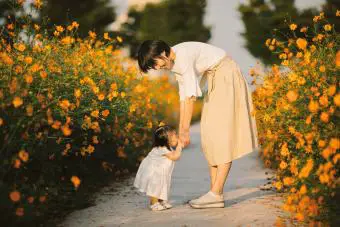 Feliz madre con bebé en campo de flores de cosmos amarillo 