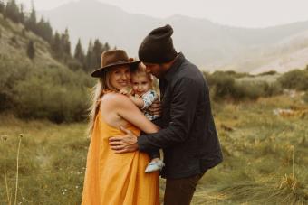 pareja abrazando a una hija pequeña en el valle rural