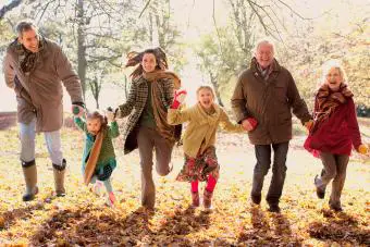 Familia extendida corriendo en el parque en otoño