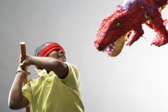 Niño preparándose para golpear la piñata de dinosaurio