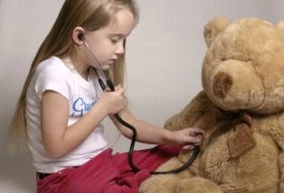 Chica examinando un oso de peluche con un estetoscopio