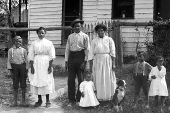 La familia negra se para frente a sus casas de la década de 1920.