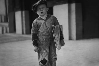 joven repartidor de noticias parado al margen vendiendo periódicos de 1925