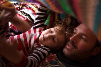 Papá y bebé bajo una manta colorida