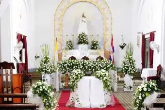 Altar con paredes blancas, telas y flores.