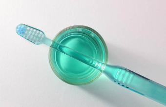Cepillo de dientes a punto de ser desinfectado en un vaso de enjuague bucal