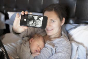La niña duerme en el pecho de la madre, mientras la madre se toma una selfie