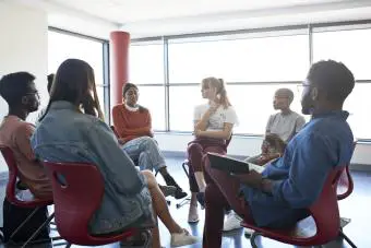 Mujer compartiendo mientras está sentada con un instructor de salud mental en una reunión de grupo