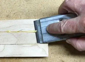 Raspe el pegamento de la madera con una cuchilla