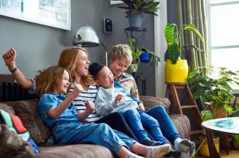Familia feliz con dos madres viendo la televisión en casa
