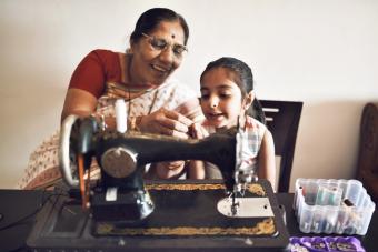 Mujer mayor que trabaja en una máquina de coser con su nieta