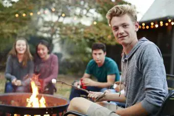 adolescentes asando malvaviscos alrededor de una fogata