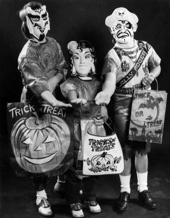 Tres niños disfrazados de Halloween y con bolsas de truco o trato 