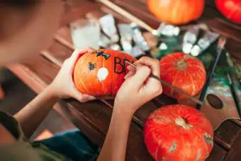 adolescente decorando calabaza de halloween con pintura