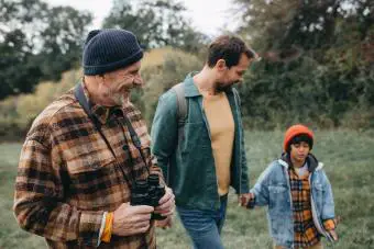 Niño con padre y abuelo caminando por el bosque 