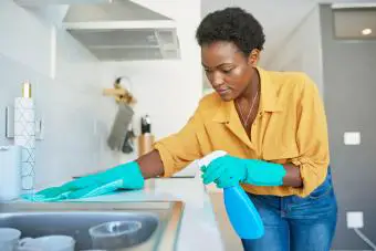 mujer joven limpiando el mostrador de la cocina en casa